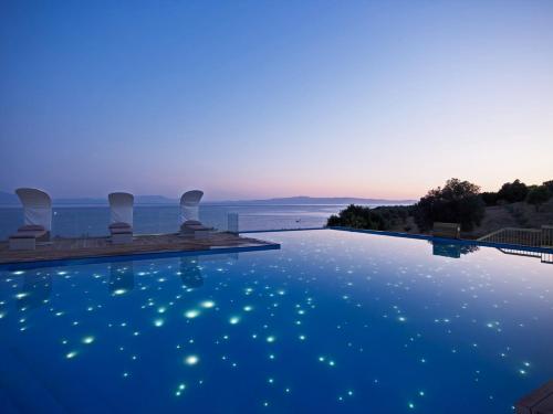 a swimming pool with a view of the ocean at dusk at Adrina Resort & Spa in Panormos Skopelos