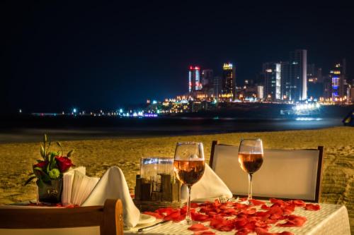 a table with wine glasses on the beach at night at Lancaster Eden Bay in Beirut