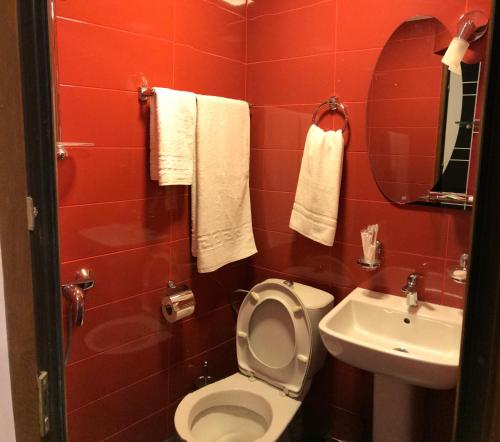 a red bathroom with a toilet and a sink at Apartment by Family Hotel in Yerevan