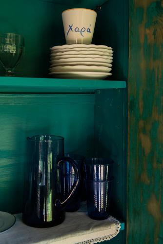 a green shelf with two cups and plates on it at Small Guesthouse In The Garden in Amarinthos