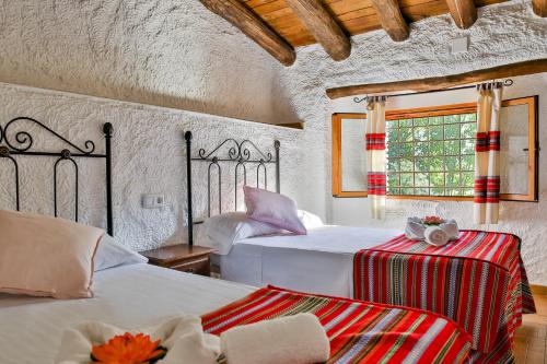 Un dormitorio con dos camas y una ventana. en Cuevas El Moral, en Castilléjar