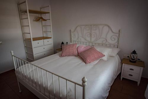 a bedroom with a white bed with two red pillows at Finca Pozo Taburiente in El Paso