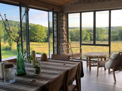 d'une salle à manger avec une table et de grandes fenêtres. dans l'établissement Domaine de Combraille en Marche, à Saint-Médard
