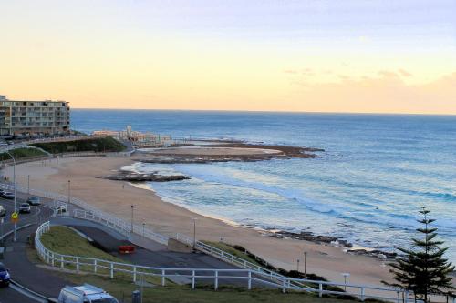 a view of a beach and the ocean at sunset at Apartment On King Street in Newcastle
