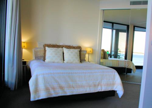 1 dormitorio con cama con almohadas y espejo en Apartment On King Street, en Newcastle