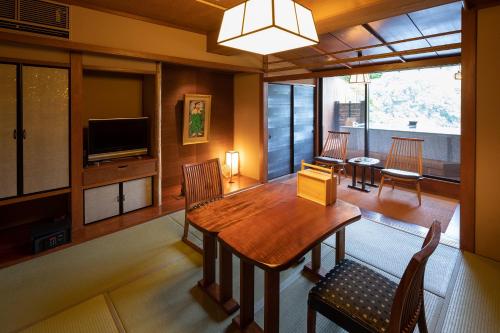a dining room with a table and a television at Watei Kazekomichi in Atami