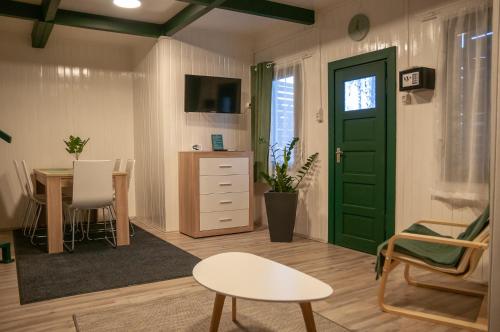 a living room with a table and a green door at Tiszavirág Panzió és Üdülőközpont in Tiszafüred