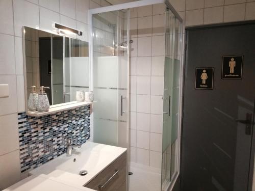 een badkamer met een wastafel en een douche met een spiegel bij Ô Temps d'Amour Sauna&Jacuzzi in Malissard