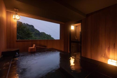 a room with a bath tub with a window at Watei Kazekomichi in Atami