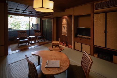 a room with a table and chairs and a television at Watei Kazekomichi in Atami