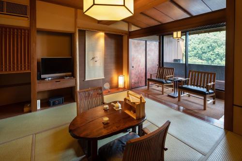a living room with a table and chairs and a television at Watei Kazekomichi in Atami