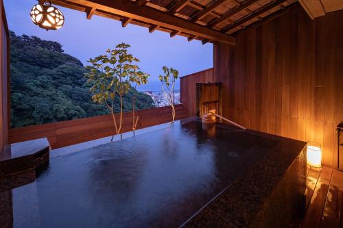 a large swimming pool in a wooden room with a view at Watei Kazekomichi in Atami