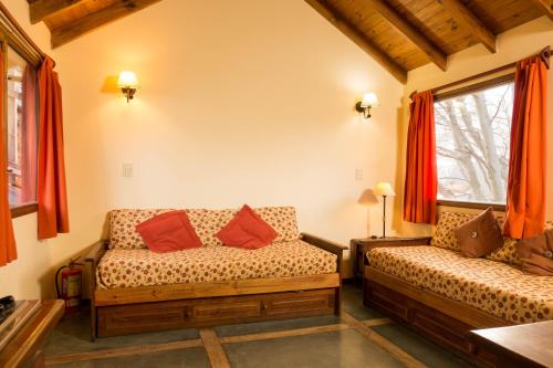 uma sala de estar com dois sofás e duas janelas em Aves del Sur em Ushuaia