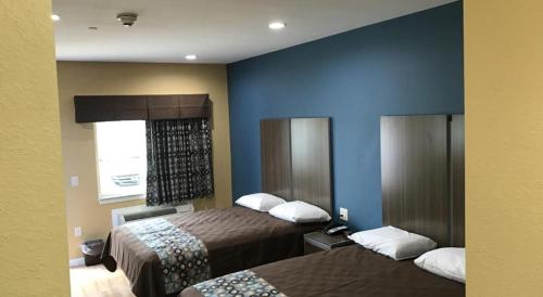 a hotel room with two beds and a window at Deluxe Inn & Suites - Baytown in Baytown