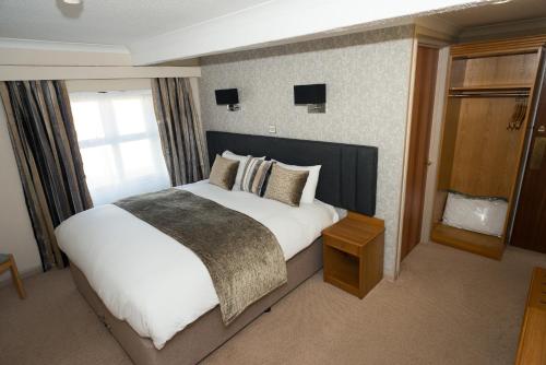 a bedroom with a large white bed and a window at Falcon Hotel in Carmarthen
