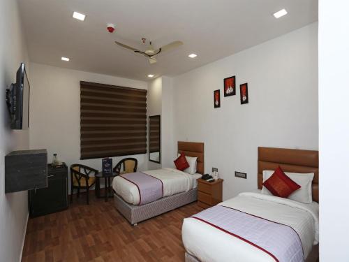 a hotel room with two beds and a table at Amora Rooms Dwarka in New Delhi