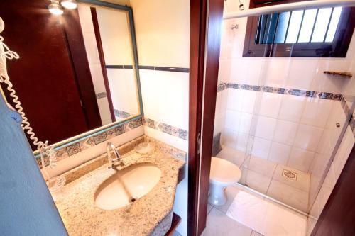 a bathroom with a sink and a shower and a toilet at Mares do Sul Pousada in Garopaba