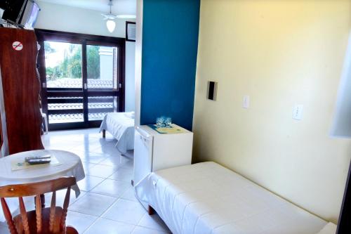 a room with a couch and a table and a refrigerator at Mares do Sul Pousada in Garopaba