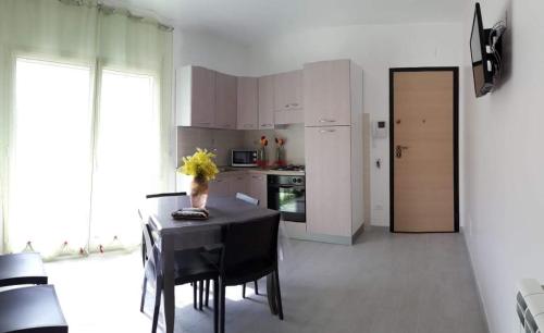 a kitchen with a table with chairs and a kitchen with white cabinets at Appartamento "Le Vele" in Castellammare del Golfo
