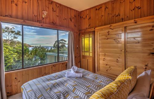 a bedroom with a bed and a large window at Beachcroft in Coles Bay