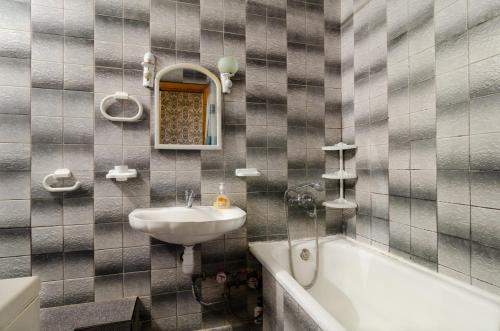 a bathroom with a sink and a tub and a mirror at Like A Home in Sumy