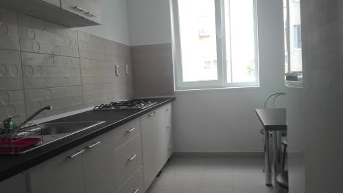 a white kitchen with a sink and a window at Apartament City in Constanţa