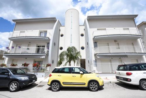 un'auto gialla parcheggiata di fronte a un edificio di Appartamento "Le Vele" a Castellammare del Golfo