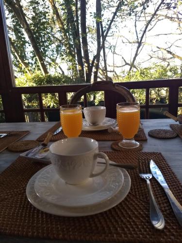 una mesa con una taza y dos vasos de zumo de naranja en Los Tarcos Guest House, en San Salvador de Jujuy
