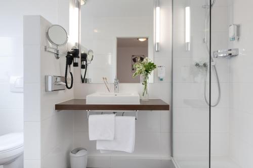 a bathroom with a sink, toilet and shower stall at Business Hotel Böblingen-Sindelfingen in Böblingen