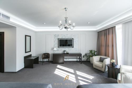 a white living room with a desk and a tv at Bon Hotel in Dnipro
