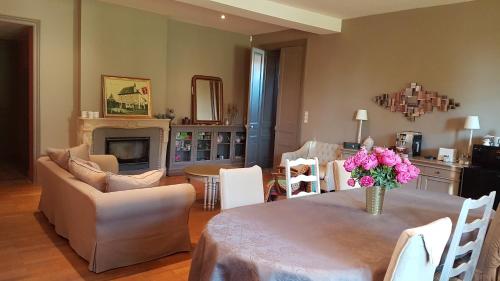 a living room with a table with a vase of flowers at Chambres d'hôtes Du Goût et des Couleurs in Grenay