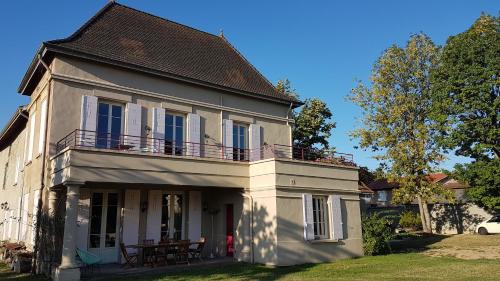a white house with a balcony and a table at Chambres d'hôtes Du Goût et des Couleurs in Grenay