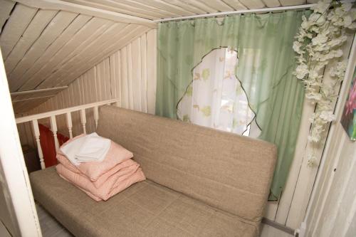 um sofá sentado numa sala com uma cortina em Апарт-коттедж White Rose-mini с зоной барбекю Выборг на природе em Vyborg