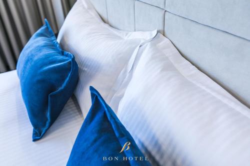 a bed with blue pillows and a blue bag on it at Bon Hotel in Dnipro