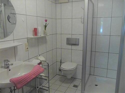 a white bathroom with a toilet and a sink at Hotel "Woiler Hof" garni in Eslohe