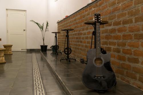 a guitar is leaning against a brick wall at Micasa Hostels in Puducherry
