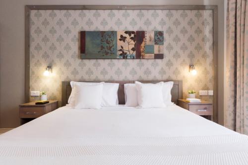 a bedroom with a large white bed with white pillows at ROOMS by Alexandra Hotel in St Julian's