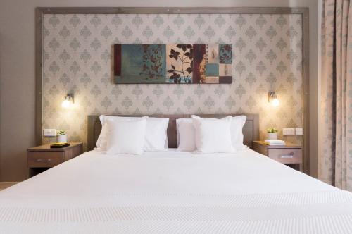 a bedroom with a large white bed with white pillows at ROOMS by Alexandra Hotel in St. Julianʼs