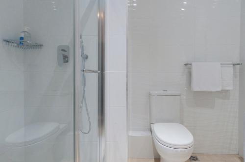 a white bathroom with a toilet and a shower at ROOMS by Alexandra Hotel in St. Julianʼs
