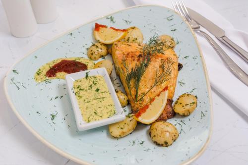 a plate with fish and potatoes and a dipping sauce at Mercure Hotel Bedfordview in Johannesburg