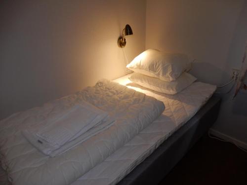 a bed with white sheets and pillows in a room at Valla Folkhögskola in Linköping