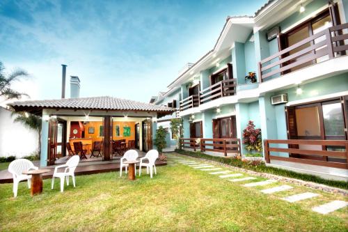 a house with white chairs and a yard at Mares do Sul Pousada in Garopaba