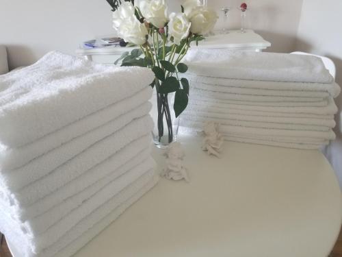 two stacks of towels on a table with a vase of flowers at Stan na dan Angel in Novi Sad