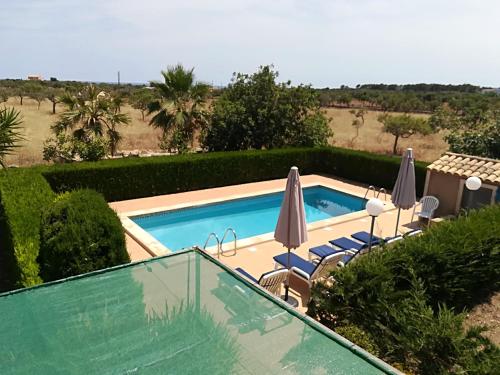 una piscina con sombrillas y sillas junto a ella en Finca Sa Gruta Marines en S'Illot