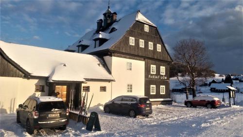 two cars parked in front of a building in the snow at Panský dům - Jizerka in Jizerka