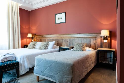 two beds in a room with red walls at Domaine de Saulon in Saulon-la-Rue