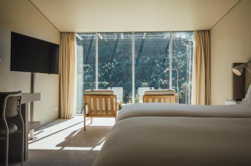a hotel room with two beds and a large window at Octant Douro in Castelo de Paiva
