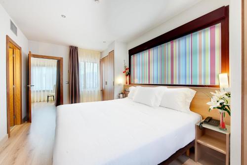 a bedroom with a white bed and a large window at Maisonnave in Pamplona