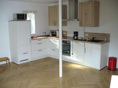 a kitchen with white cabinets and a wooden floor at Ferienwohnung Riedner in Lüneburg