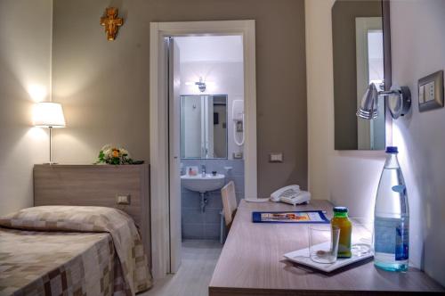 アッシジにあるDomus Pacis Assisiのベッドルーム1室(ベッド1台、テーブル、ボトル1本付)